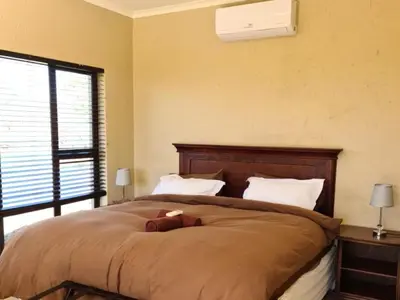 a bedroom with a bed with a teddy bear on it at Lion and Cheetah Sanctuary in Cullinan