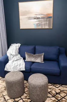 a blue couch in a living room with two ottoman at Triple M Luxury in Vosburg