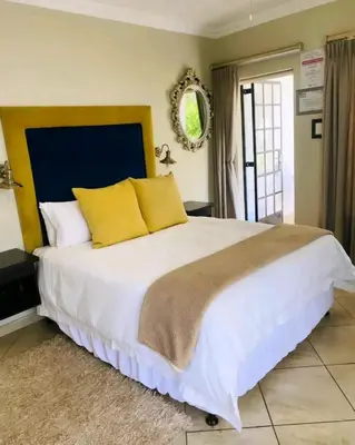 a bedroom with a large white bed with yellow pillows at Destiny Lodge Cullinan in Cullinan