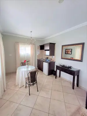 a living room with a table and a kitchen at Destiny Lodge Cullinan in Cullinan