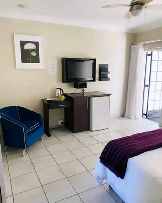 a bedroom with a bed and a tv and a chair at Destiny Lodge Cullinan in Cullinan