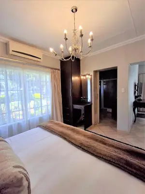 a bedroom with a large bed and a chandelier at Destiny Lodge Cullinan in Cullinan