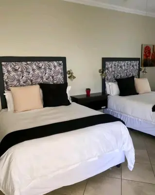 a bedroom with two beds with white and black at Destiny Lodge Cullinan in Cullinan