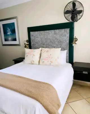 a bedroom with a white bed with a fan at Destiny Lodge Cullinan in Cullinan
