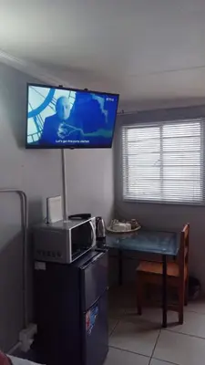 a living room with a tv on the wall at The Croc Backpackers in Springs