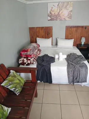 a bedroom with a large bed and a bench at The Croc Backpackers in Springs