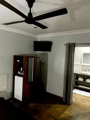 a living room with a ceiling fan and a mirror at Phatt Olive BnB in Middelburg