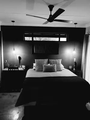 a black bedroom with a bed with a ceiling fan at Phatt Olive BnB in Middelburg