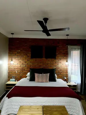 a bedroom with a large bed with a ceiling fan at Phatt Olive BnB in Middelburg