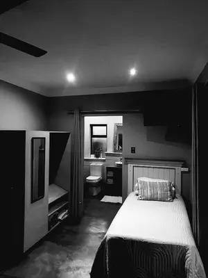 a black and white bedroom with a bed and a bathroom at Phatt Olive BnB in Middelburg