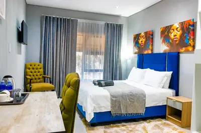 a bedroom with a king sized bed and a chair at Glowti Event & Guest House in Centurion