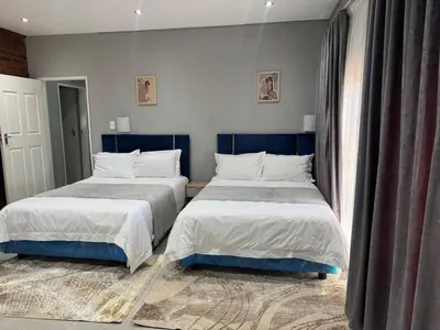 two beds sitting next to each other in a bedroom at Glowti Event & Guest House in Centurion