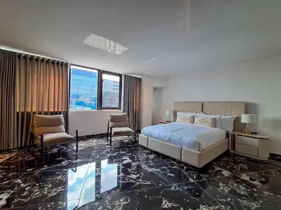 a bedroom with a bed and two chairs in it at Pent Lucius - 3 bedroom Penthouse in Pretoria