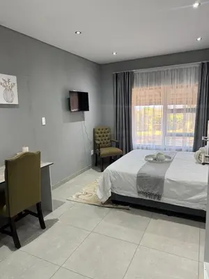 a bedroom with a bed and a desk and a window at Glowti Guest House in Centurion