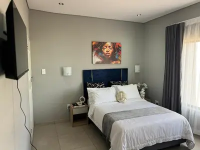 a bedroom with a bed and a painting on the wall at Glowti Guest House in Centurion