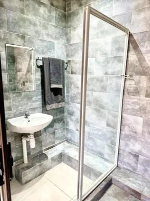 a bathroom with a shower and a sink at Glowti Guest House in Centurion