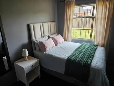 a bedroom with a bed with pink pillows and a window at Beautiful apartment in Witbank
