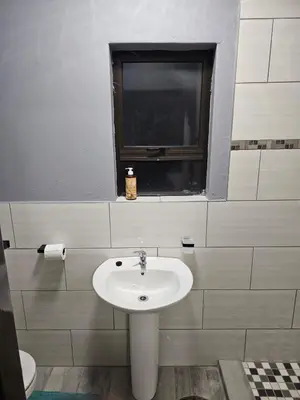 a bathroom with a white sink and a window at Beautiful apartment in Witbank