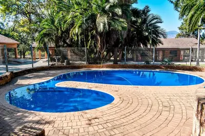 a large blue swimming pool with a brick walkway around it at Twin Bed Room in Steelpoort