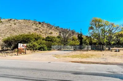 an empty road next to a hill with a fence at Twin Bed Room in Steelpoort