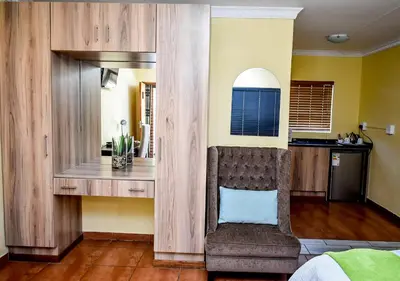 a living room with a chair and a kitchen at Twin Bed Room in Steelpoort