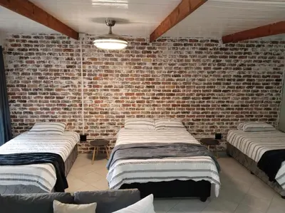 a room with three beds against a brick wall at Duikertjie in Groblersdal