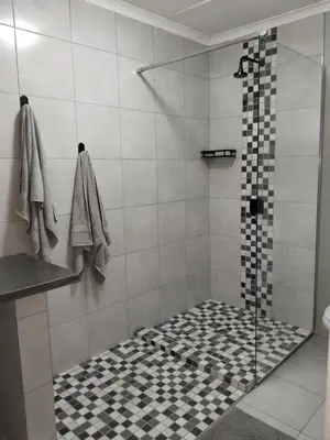 a shower with a black and white tiled floor at Duikertjie in Groblersdal