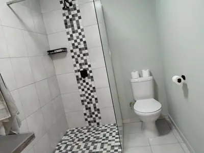 a bathroom with a shower with a toilet and a checkered tile floor at Duikertjie in Groblersdal