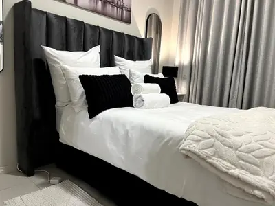 a bedroom with a large white bed with black pillows at Cozy Carlswald EXcape in Midrand
