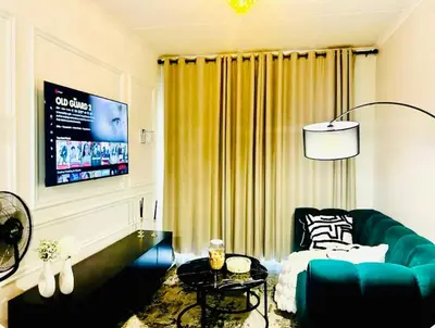 a living room with a green couch and a tv at Cozy Carlswald EXcape in Midrand