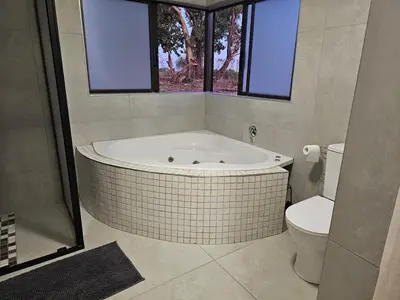 a bathroom with a bath tub and a toilet at Outerspaces Farmhouse Retreat