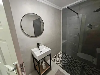 a bathroom with a sink and a mirror and a shower at Outerspaces Farmhouse Retreat