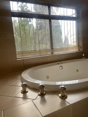 a bath tub in a bathroom with a window at Bugera's Palace in Pretoria