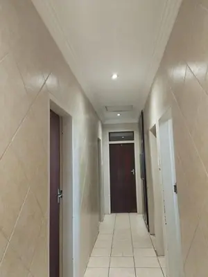 a hallway of a building with a door and a tile floor at Queen Guest House in Pretoria