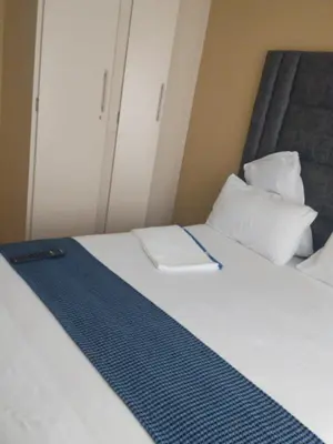 a bedroom with a bed with white sheets and pillows at Queen Guest House in Pretoria