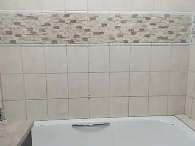 a white tiled bathroom with a bath tub at Queen Guest House in Pretoria