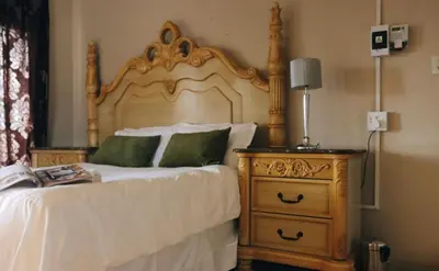 a bedroom with a bed with a wooden headboard and a night stand at 54 River Logde in Mokopane