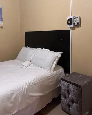 a bed with a black headboard and white pillows at 54 River Logde in Mokopane