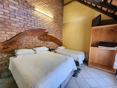 a bedroom with two beds and a brick wall at Mukurumanzi Lodge in Polokwane