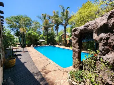 a swimming pool in a yard next to a building at Mukurumanzi Lodge in Polokwane