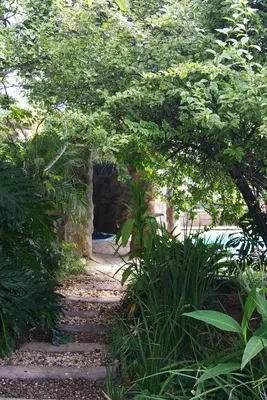 a stone path through a tunnel with trees and plants at Mukurumanzi Lodge in Polokwane