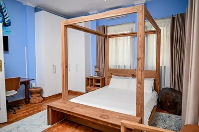a bedroom with a wooden canopy bed with white sheets at CasaRegalo180 in Pretoria