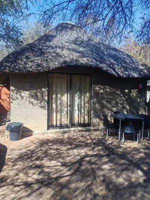 a hut with a thatched roof with a table and chairs at Aloe Bush Game Lodge in Marble Hall
