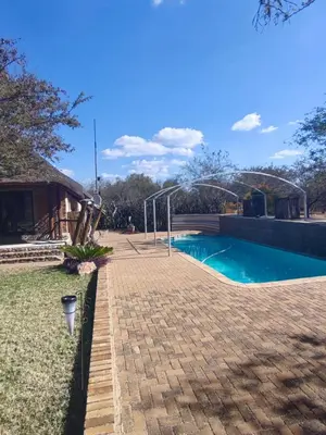 a swimming pool in a yard next to a house at Aloe Bush Game Lodge in Marble Hall