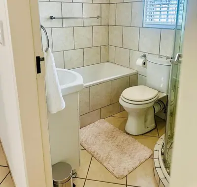a bathroom with a toilet and a tub and a sink at BKM Retreat Lake View in Pretoria