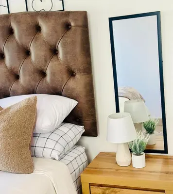 a bedroom with a brown headboard and a table with a lamp at BKM Retreat Lake View in Pretoria