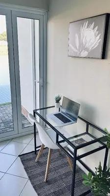 a glass table with a laptop sitting on a chair at BKM Retreat Lake View in Pretoria