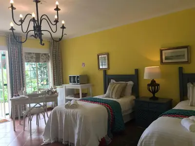 a bedroom with two beds and a table and a desk at Diggersrest Lodge in Haenertsburg