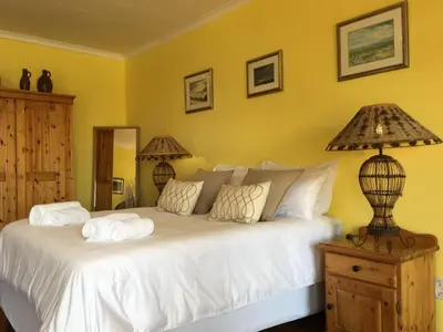 a bedroom with a large bed with white sheets at Diggersrest Lodge in Haenertsburg