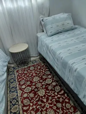 a bedroom with a bed with a table and a rug at Shalom self catering Cottage in Centurion